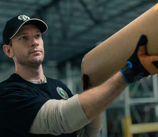 Old Dominion Freight Line employee handling a large shipping tube in a warehouse.